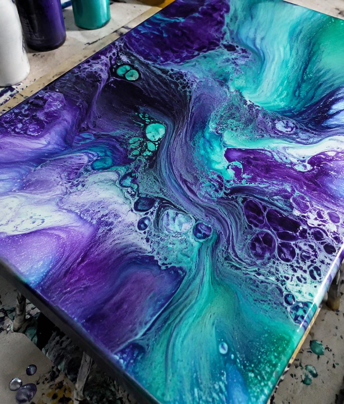 Violet and teal pigment blooming across a tilted canvas